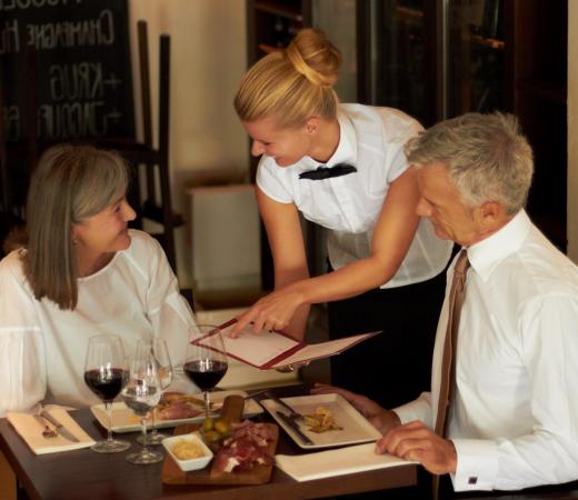 A waitress explains the menu to her customers, subtly up-selling certain items.